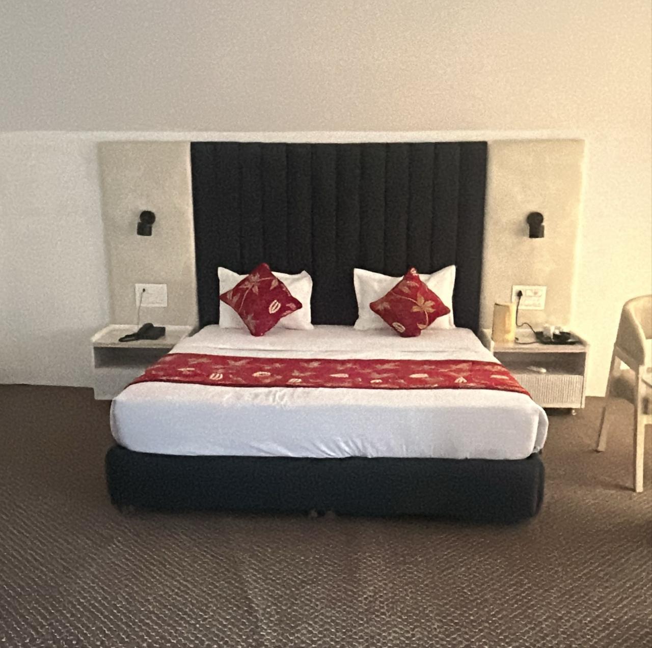 Double bed with red cushions and a dark upholstered headboard